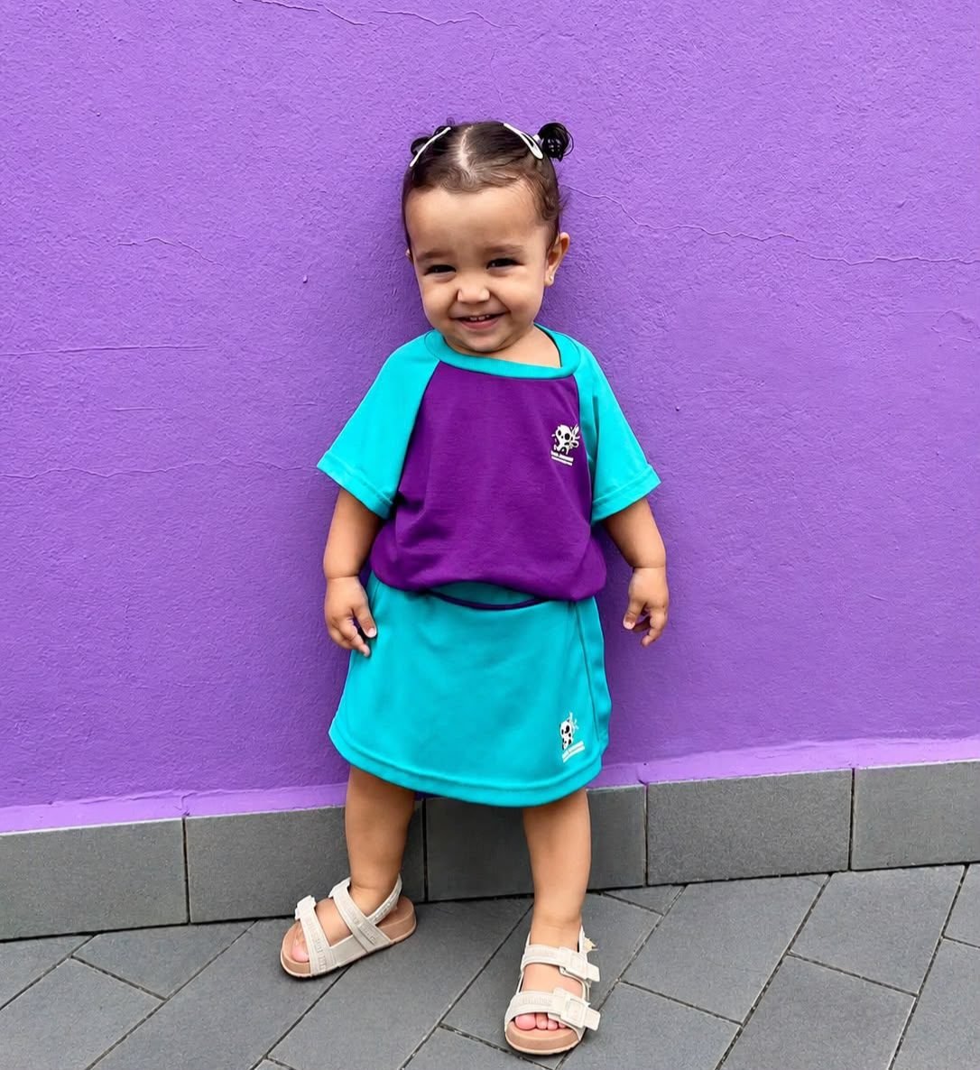 Criança sorrindo com o uniforme roxo e turquesa da Doce Sonhar
