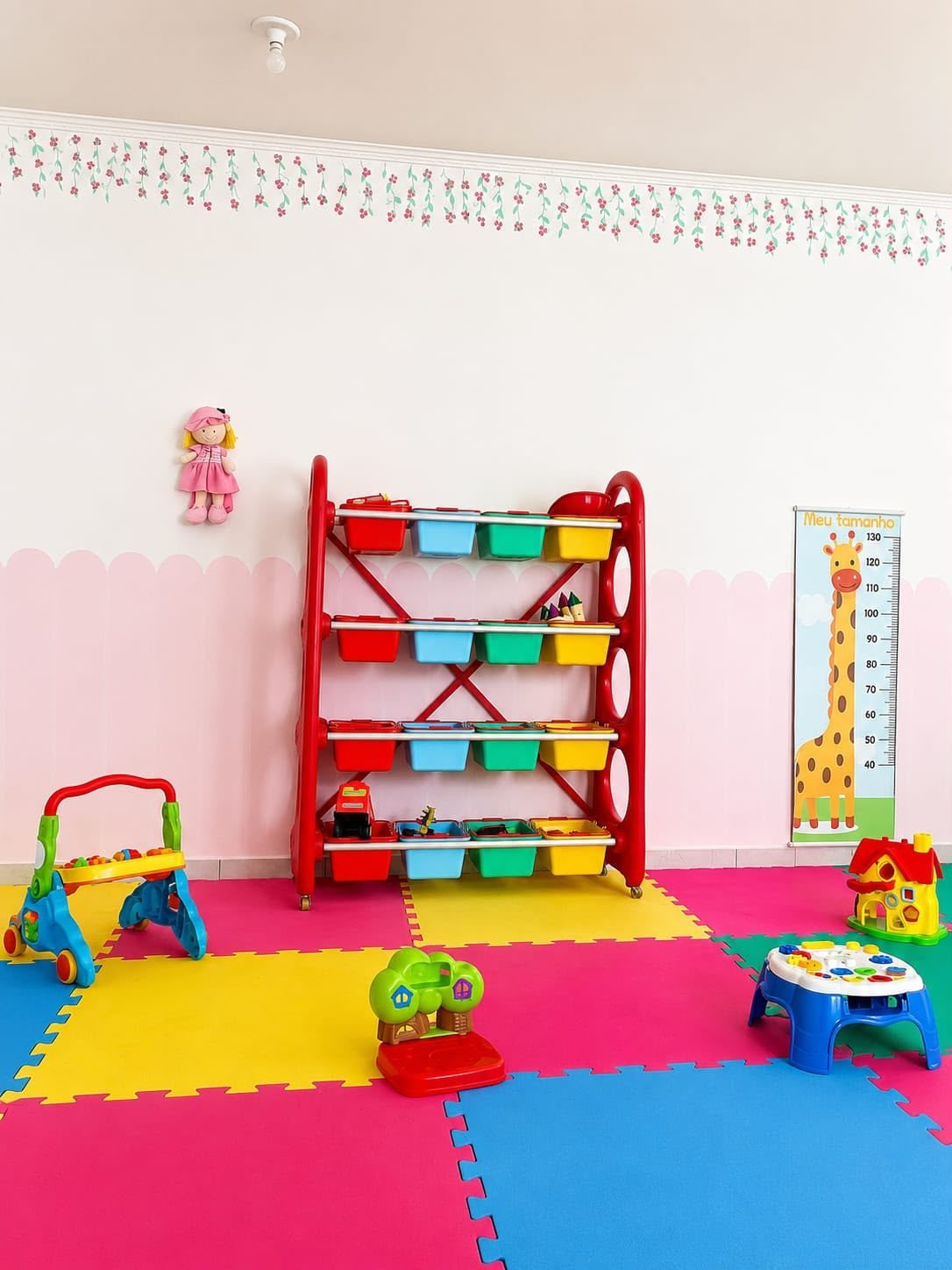 Área de brincadeira com tatames coloridos e estante de brinquedos
