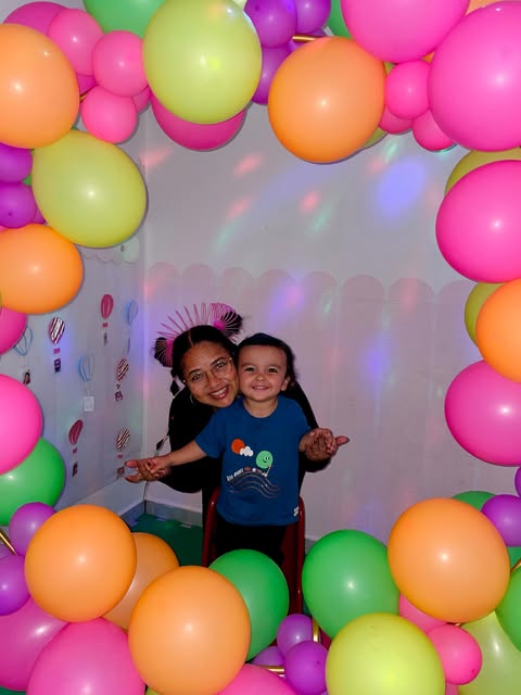 Professora e menino sorrindo entre balões