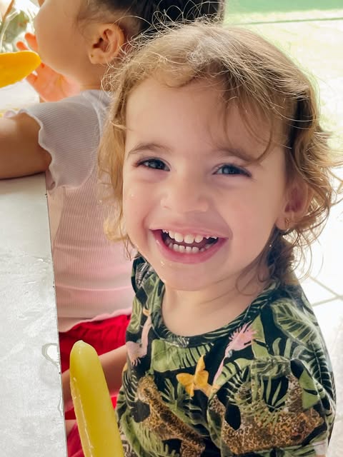 Menina gargalhando com um picolé na mão